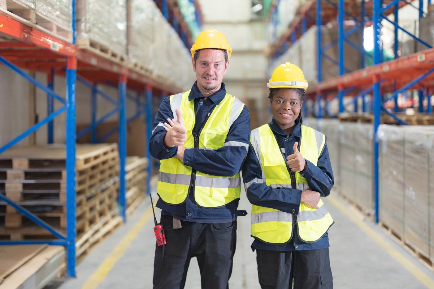 Two warehouse workers smile happily.